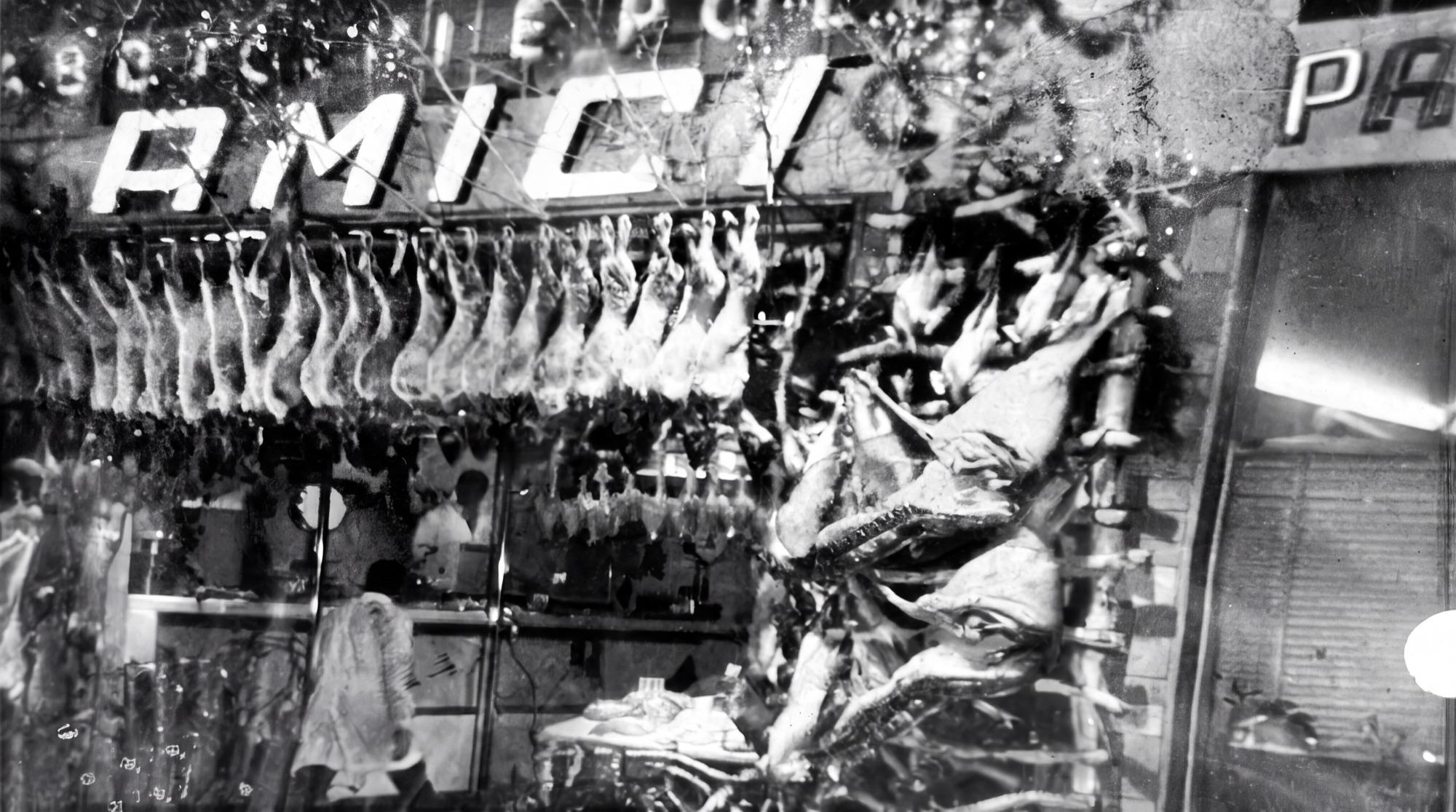 La vetrina della macelleria Amici in via Pantelleria, al Tufello, con l'insegna al neon e la carne appesa